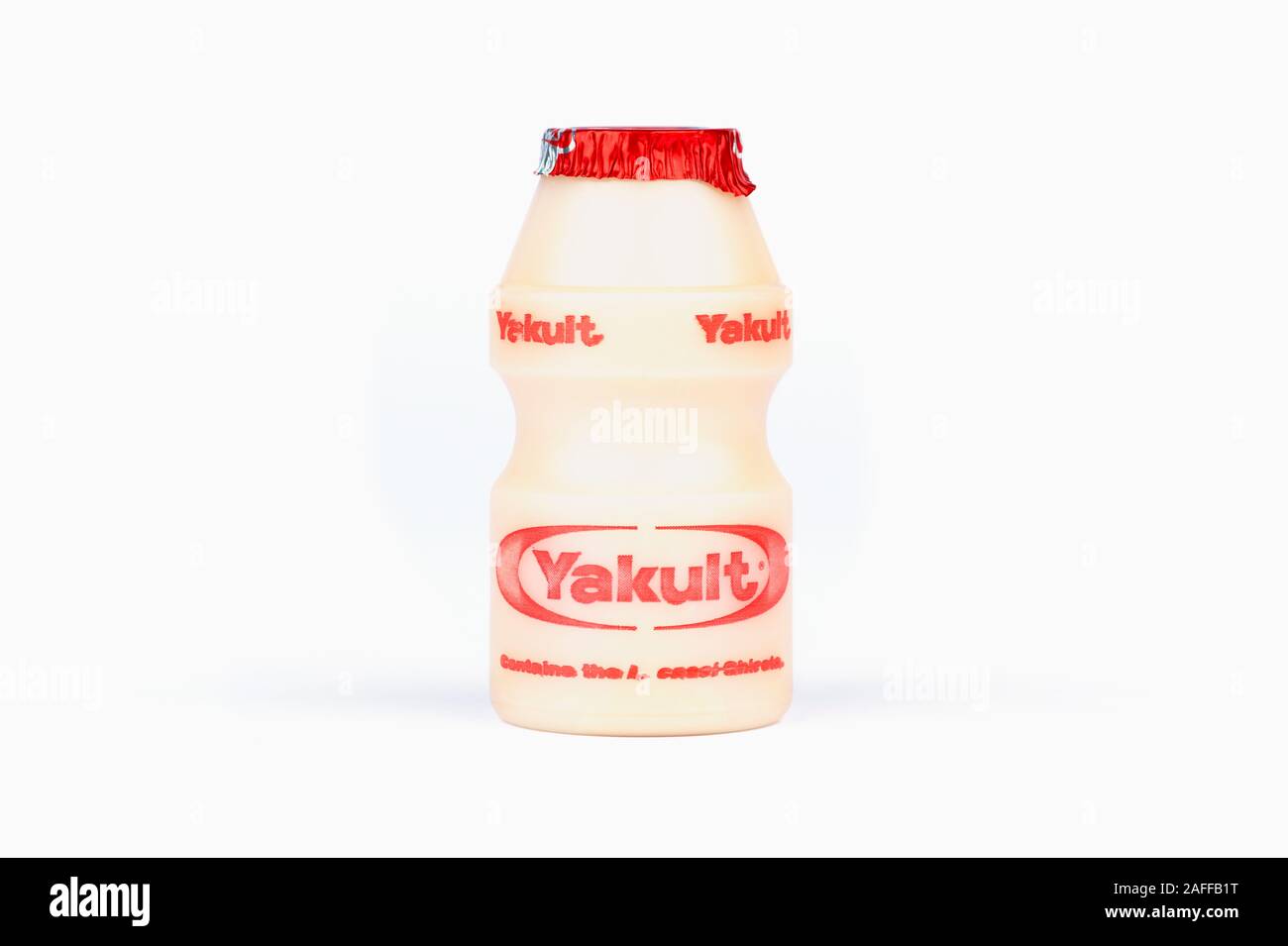Une petite bouteille de boisson de lait probiotique sucré Yakult tourné sur un fond blanc. Banque D'Images
