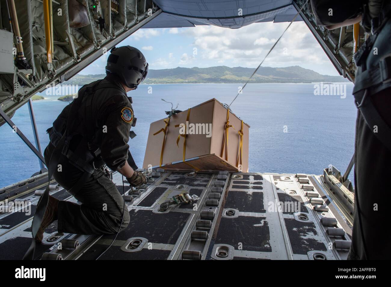 U.S. Air Force Tech. Le Sgt. Mario Montoya gouttes d'air à basse altitude d'un ensemble contenant des fournitures et des dons à l'arrière d'un C-130 de l'USAF Super Hercules 5 décembre 2019 plus de Micronésie. Au cours des 68-ans, la U.S. Air Force Operation Christmas Drop a fourni des fournitures essentielles à 56 îles micronésiennes, touchant environ 20 000 personnes à travers un 1,8 million de milles marins carrés. Banque D'Images