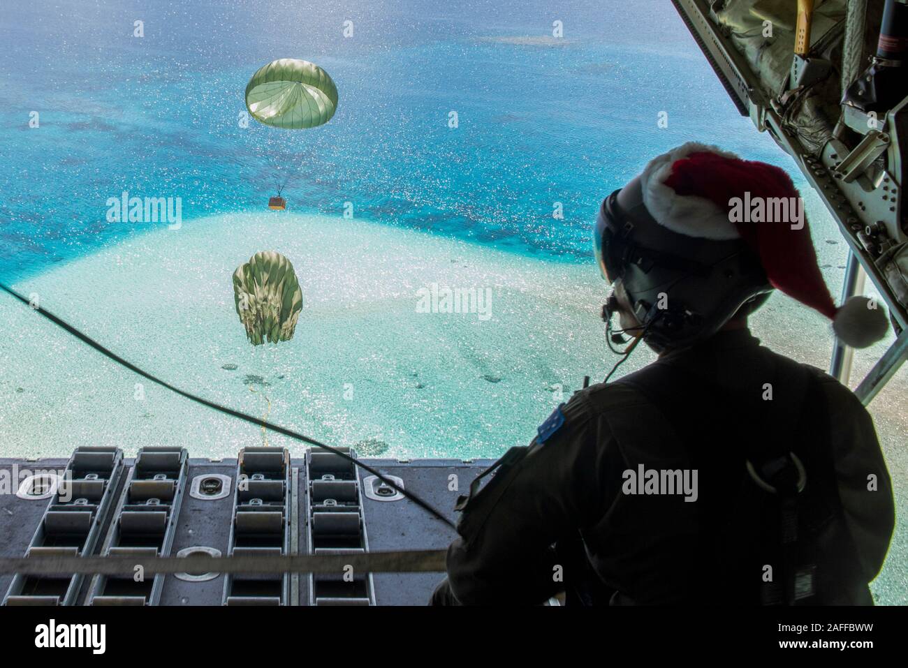 Royal Australian Air Force SGT Karl Penny de parachutage à basse altitude d'un ensemble contenant des fournitures et des dons à l'arrière d'un RAAF C-130J Super Hercules 13 décembre 2019 sur l'Atoll Kapingamarangi, États fédérés de Micronésie. Au cours des 68-ans, la U.S. Air Force Operation Christmas Drop a fourni des fournitures essentielles à 56 îles micronésiennes, touchant environ 20 000 personnes à travers un 1,8 million de milles marins carrés. Banque D'Images