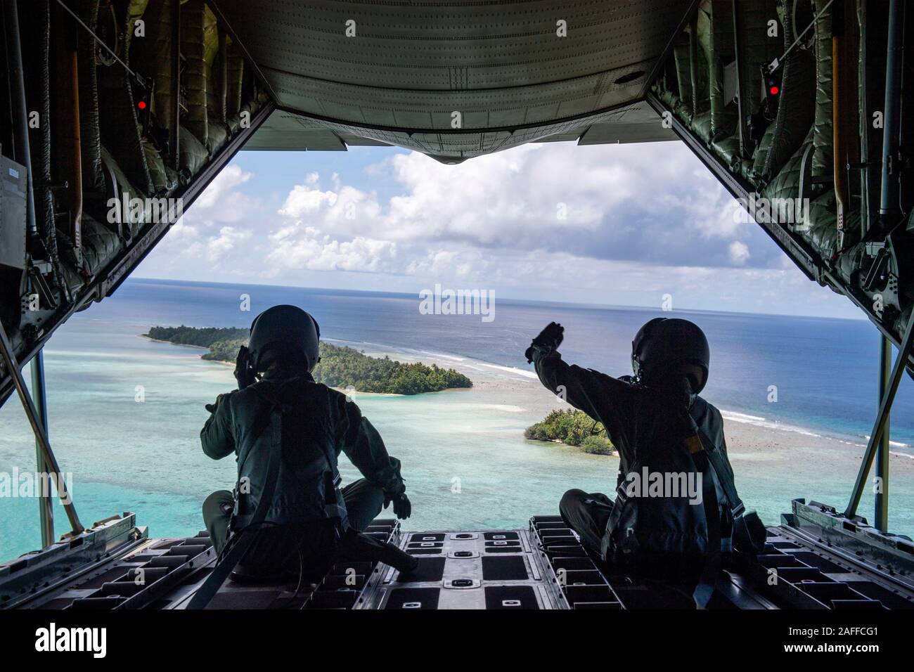 Auto-défense japonaises aviateurs vague à l'île après la chute de l'air à basse altitude d'un ensemble contenant des fournitures et cadeaux 12 décembre 2019 plus de Magur, Chuuk, États fédérés de Micronésie. Au cours des 68-ans, la U.S. Air Force Operation Christmas Drop a fourni des fournitures essentielles à 56 îles micronésiennes, touchant environ 20 000 personnes à travers un 1,8 million de milles marins carrés. Banque D'Images