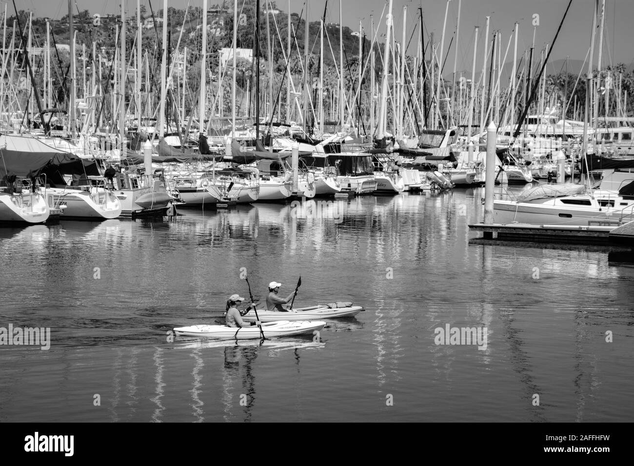 Un ajustement, couple d'âge moyen de leurs manœuvres kayaks autour du quai voiliers et yachts dans la marina au port de Santa Barbara, Santa Barbara, CA, Banque D'Images