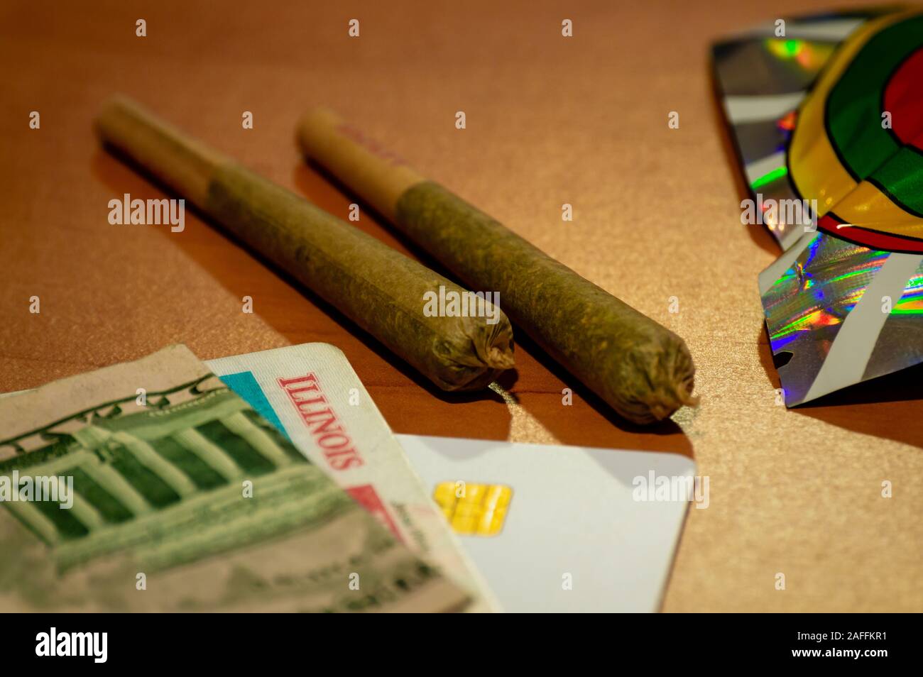 La légalisation du cannabis récréatif dans l'Illinois. Deux joints de marijuana sont affichées avec une carte d'identité de l'Illinois et de l'argent sur une table. Banque D'Images