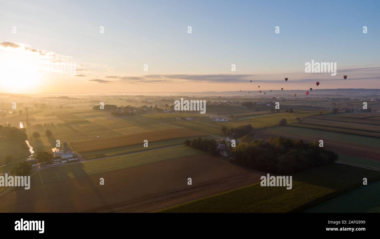 Ballons à air chaud s'élever dans l'air au-dessus de la campagne américaine en Pennsylvanie, plusieurs dirigeables aéroporté planeur au-dessus de terres agricoles Banque D'Images