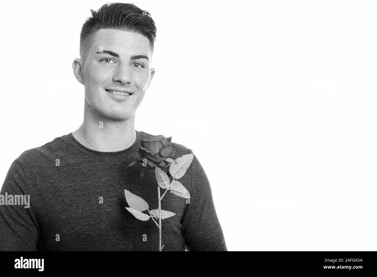 Studio shot of happy handsome man smiling while holding red rose Banque D'Images