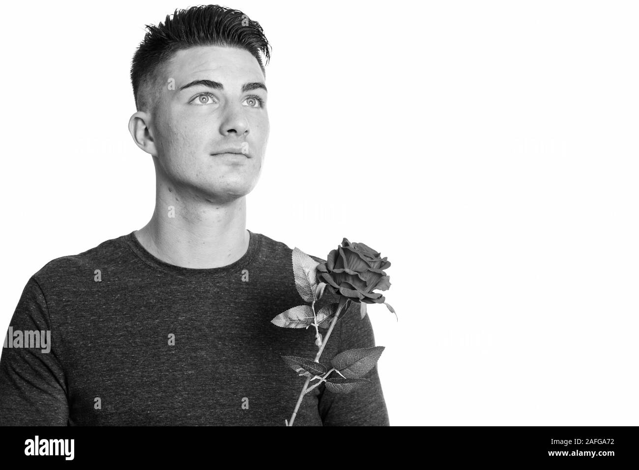 Portrait of young man holding red rose en pensant Banque D'Images