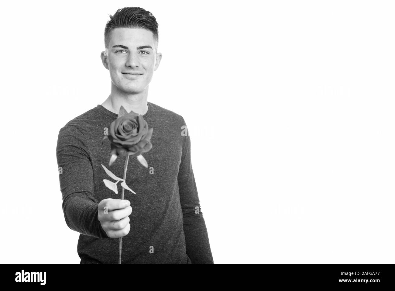 Studio shot of happy handsome man smiling tout en donnant la rose rouge Banque D'Images