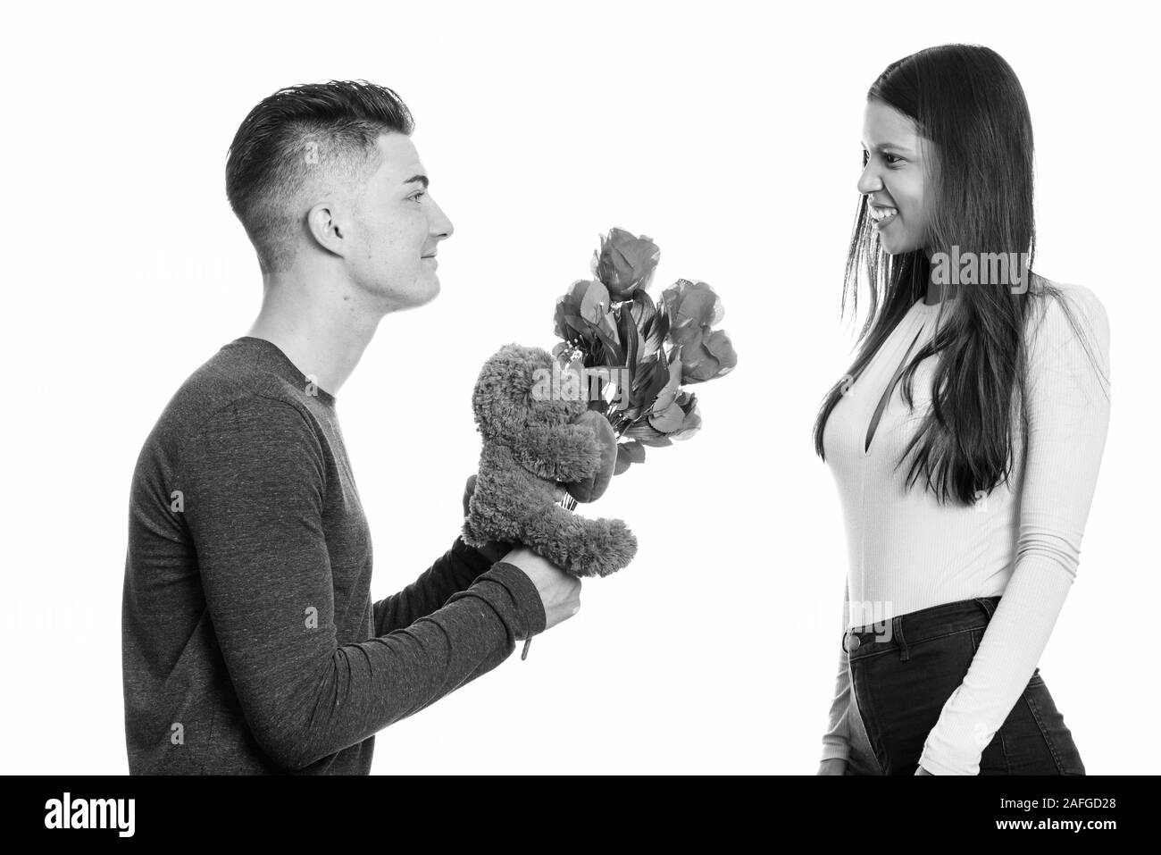 Jeune couple heureux et amoureux de l'homme donnant des roses rouges et ours Banque D'Images