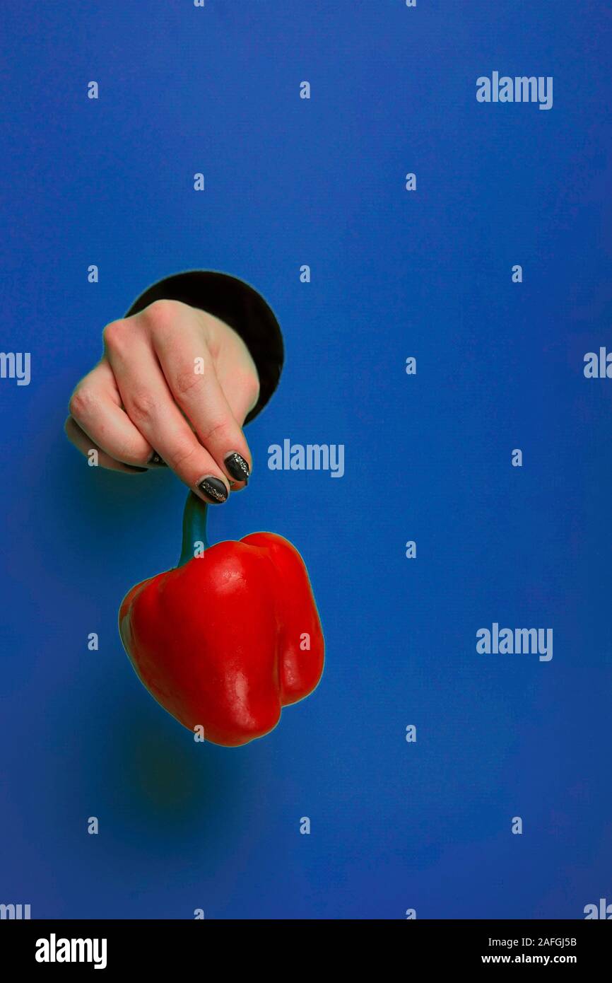 La main féminine dans un trou circulaire dans l'arrière-plan tendance bleu Banque D'Images