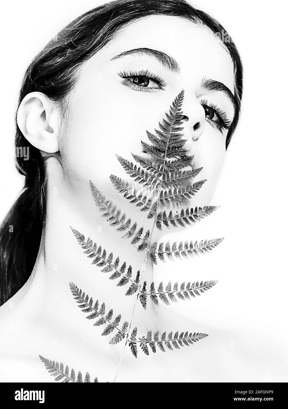 Portrait d'un adulte femme brune sur un fond blanc avec des soins de la peau, fougère vert concept, une belle peau et des mains avec manucure ongle. Banque D'Images