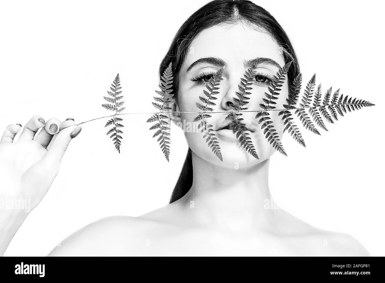 Portrait d'un adulte femme brune sur un fond blanc avec des soins de la peau, fougère vert concept, une belle peau et des mains avec manucure ongle. Banque D'Images