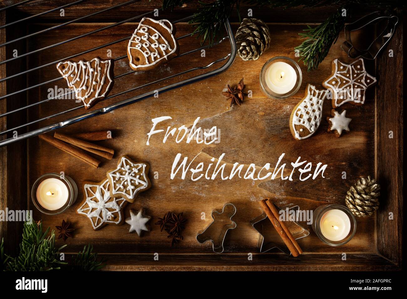 D'épices, de bougies et d'un emporte-pièce sur un plateau de bois foncé, texte allemand Frohe Weihnachten, sens joyeux Noël, télévision lay, high angle v Banque D'Images