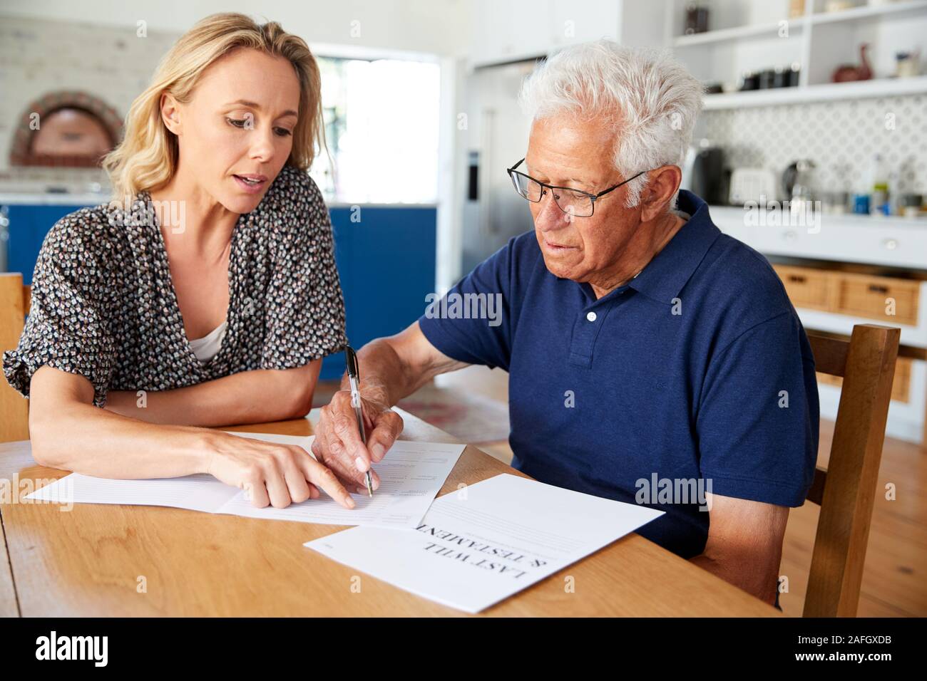 Woman Helping Senior Man pour terminer Dernier Testament à la maison Banque D'Images