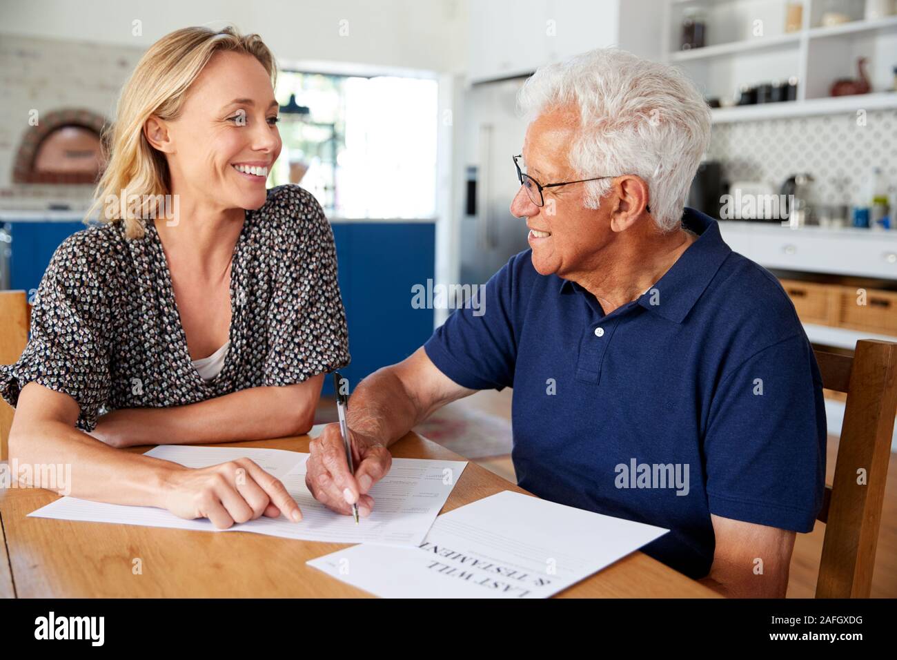 Woman Helping Senior Man pour terminer Dernier Testament à la maison Banque D'Images