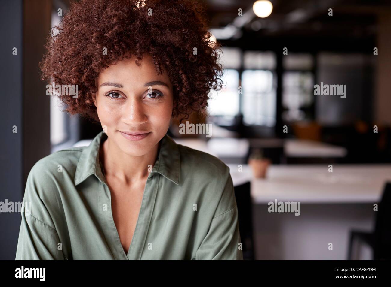 Portrait de femme noire millénaire dans une séance créative open plan office smiling to camera Banque D'Images