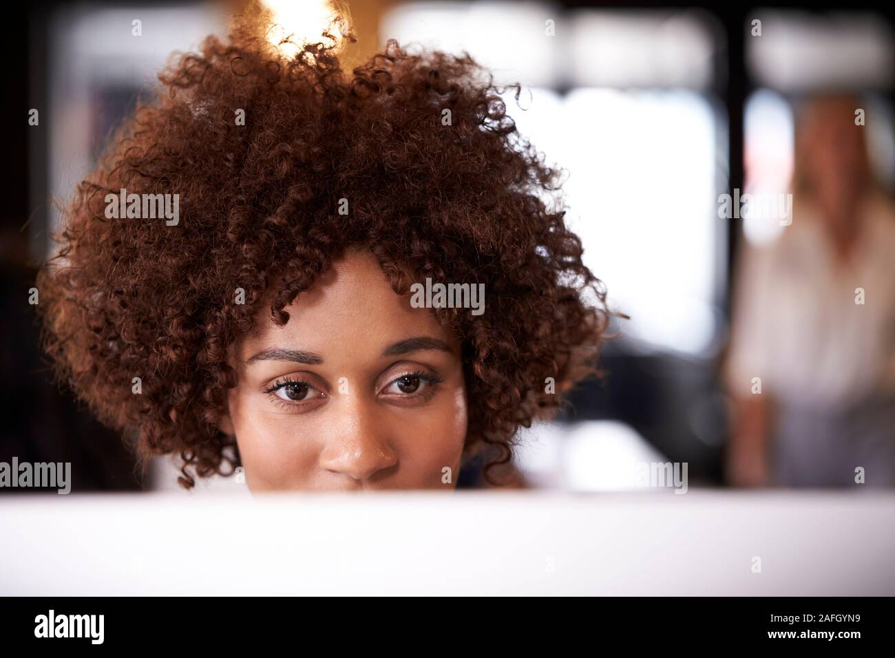 Portrait de femme noire millénaire à l'aide de création à un bureau de l'ordinateur dans un bureau, head shot Banque D'Images