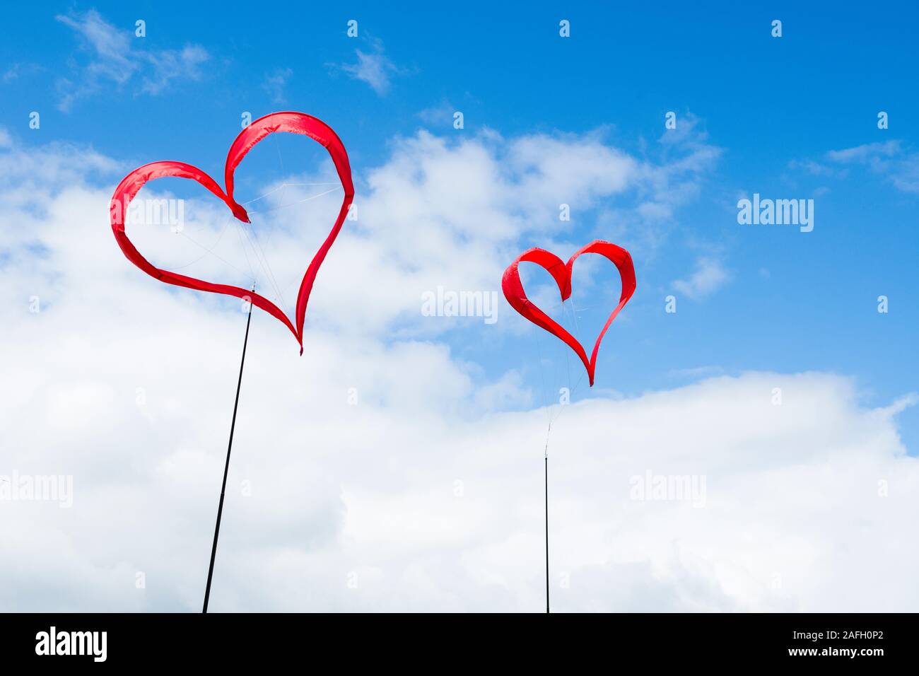 Deux cerfs-volants en forme de coeur rouge sur un ciel bleu avec des nuages blancs Banque D'Images