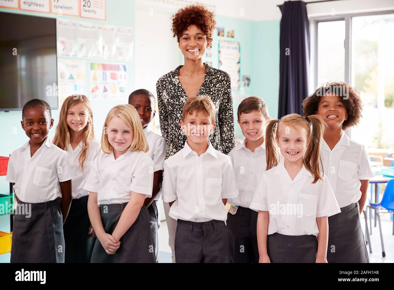 Portrait des élèves de l'élémentaire en uniforme debout en classe avec des enseignants de sexe féminin Banque D'Images