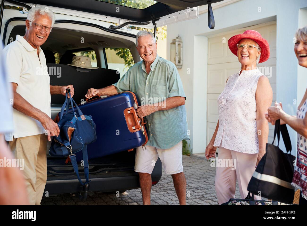 Groupe d'amis charger des bagages dans coffre de voiture sur le point de partir pour des vacances Banque D'Images