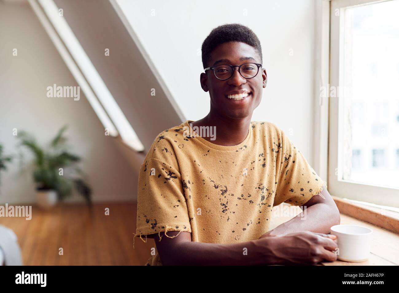 Portrait of Young Man Relaxing In Loft avec boisson chaude Banque D'Images