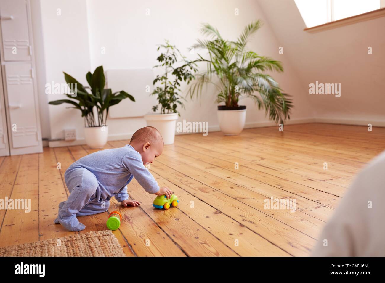 Bébé Garçon jouant avec des jouets sur le plancher à la maison Banque D'Images