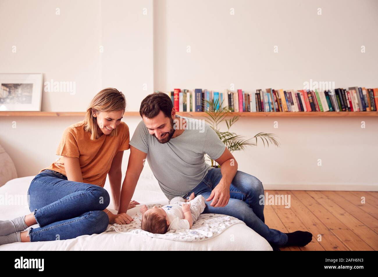 Les parents aimants avec nouveau-né Baby Lying On Bed At Home in Loft Apartment Banque D'Images