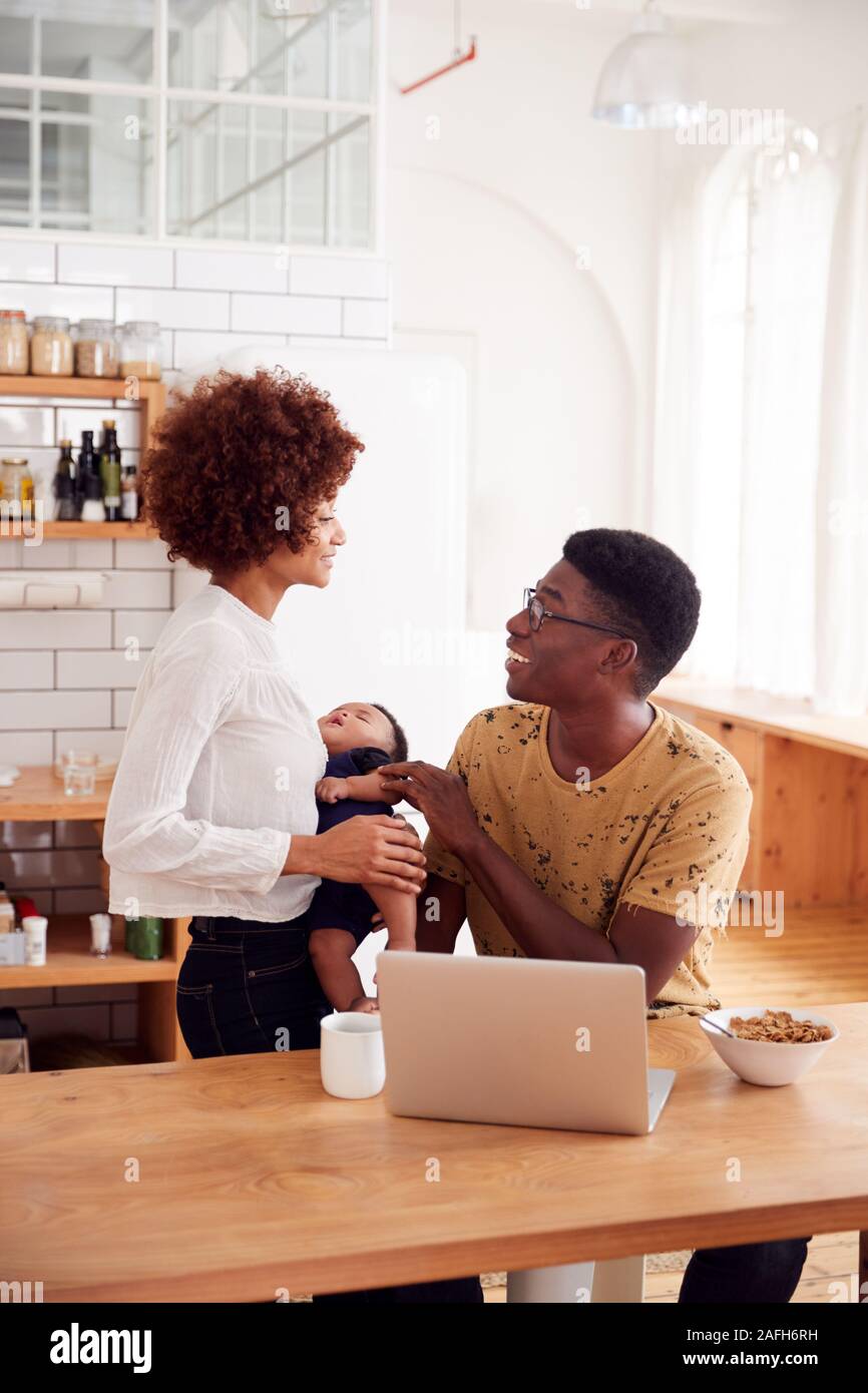 Famille occupée dans la cuisine au petit-déjeuner avec le père s'occuper de son bébé Banque D'Images