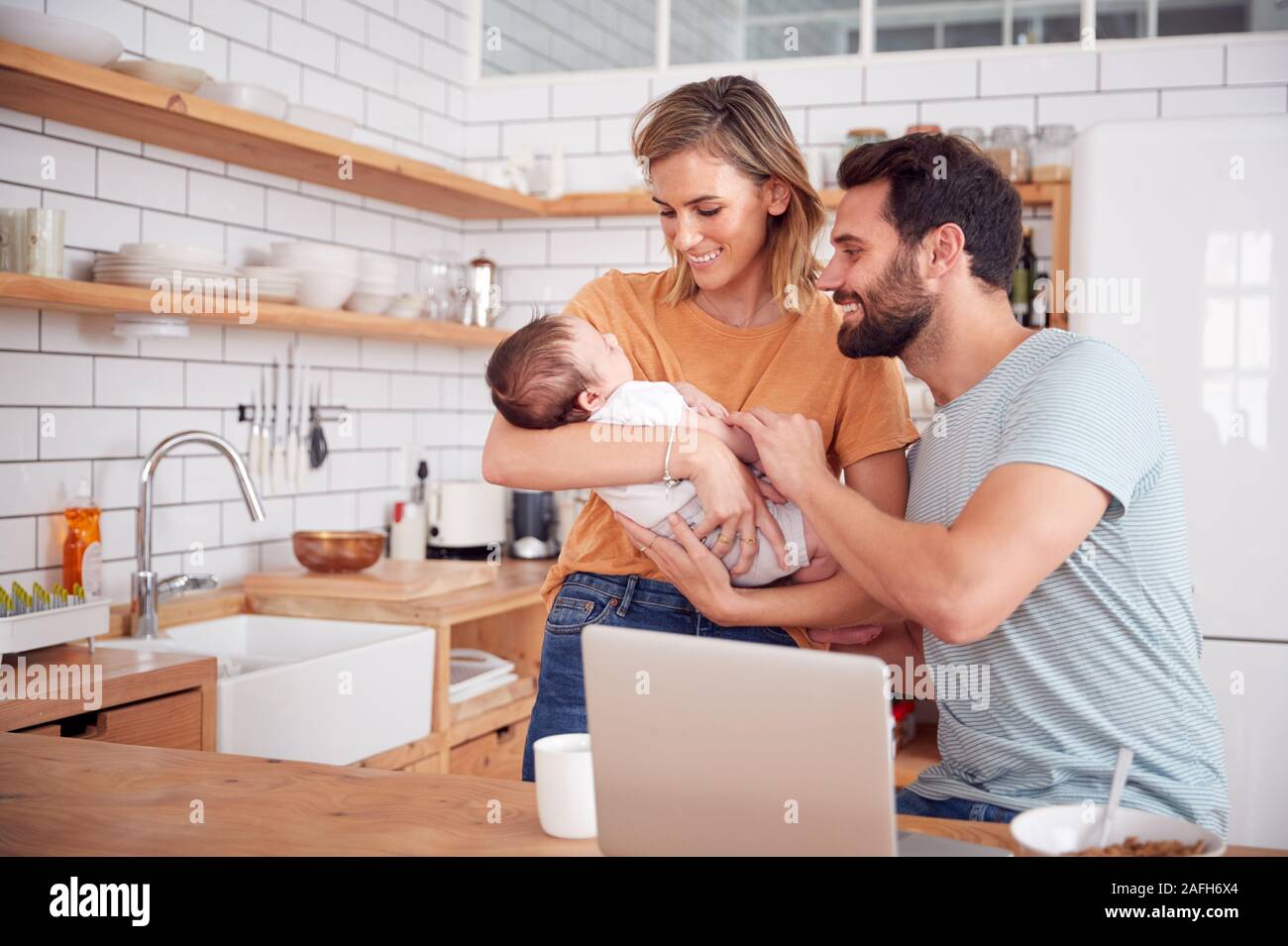 Famille occupée dans la cuisine au petit-déjeuner avec la mère s'occuper de son bébé Banque D'Images