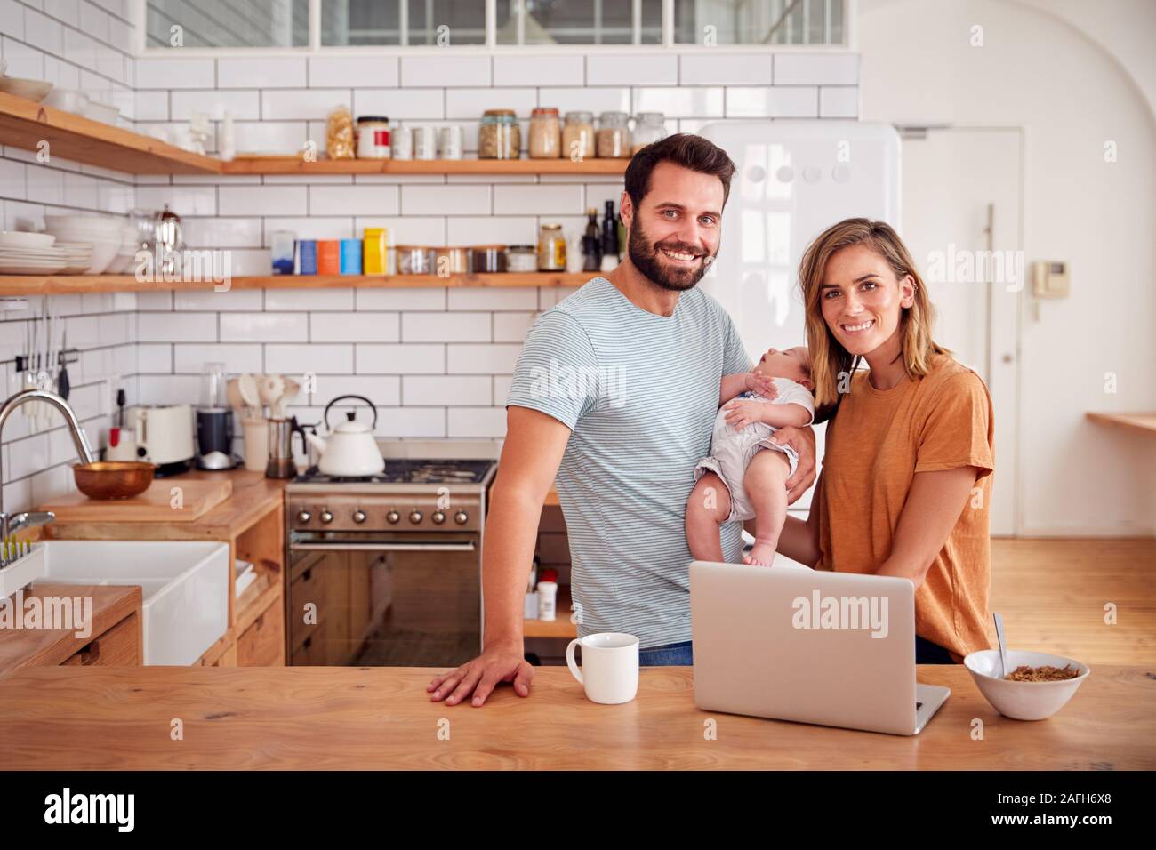 Portrait de famille occupée dans la cuisine au petit-déjeuner avec le père s'occuper de son bébé Banque D'Images