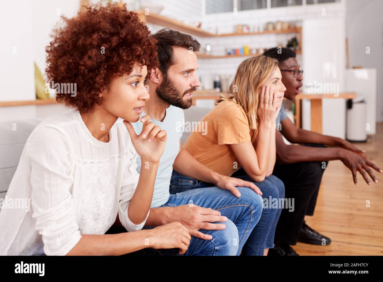 Heureux Groupe d'amis assis sur un canapé et regarder du sport à la télévision Banque D'Images