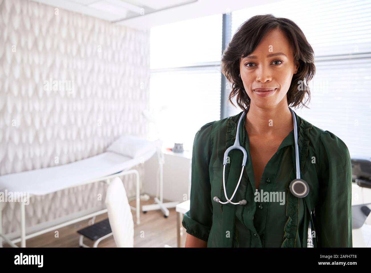 Portrait Of Smiling Female Doctor with Stethoscope Standing By Desk In Office Banque D'Images