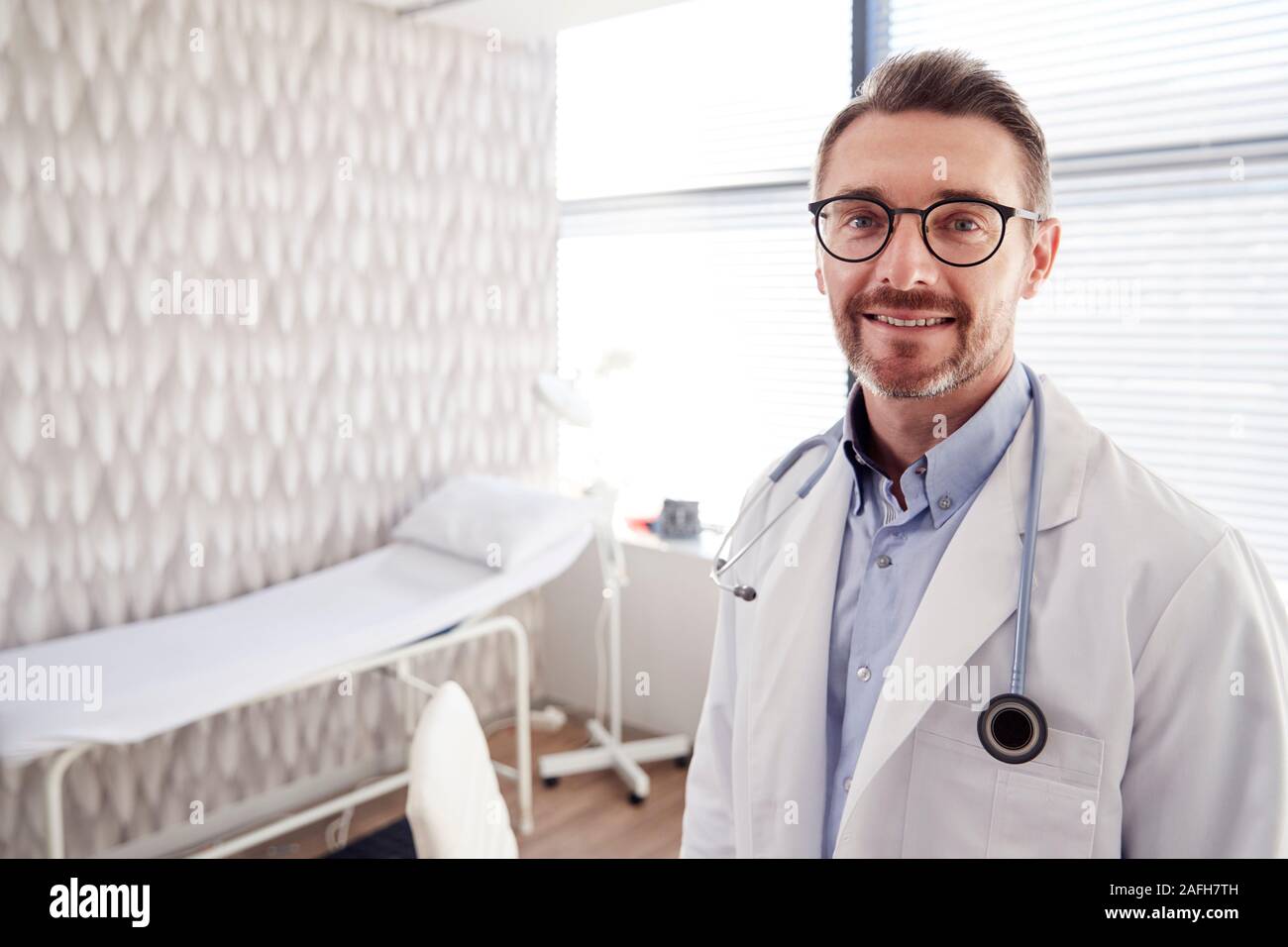 Portrait Of Smiling Mature Male Doctor Wearing White Coat with colleagues Standing In Office Banque D'Images