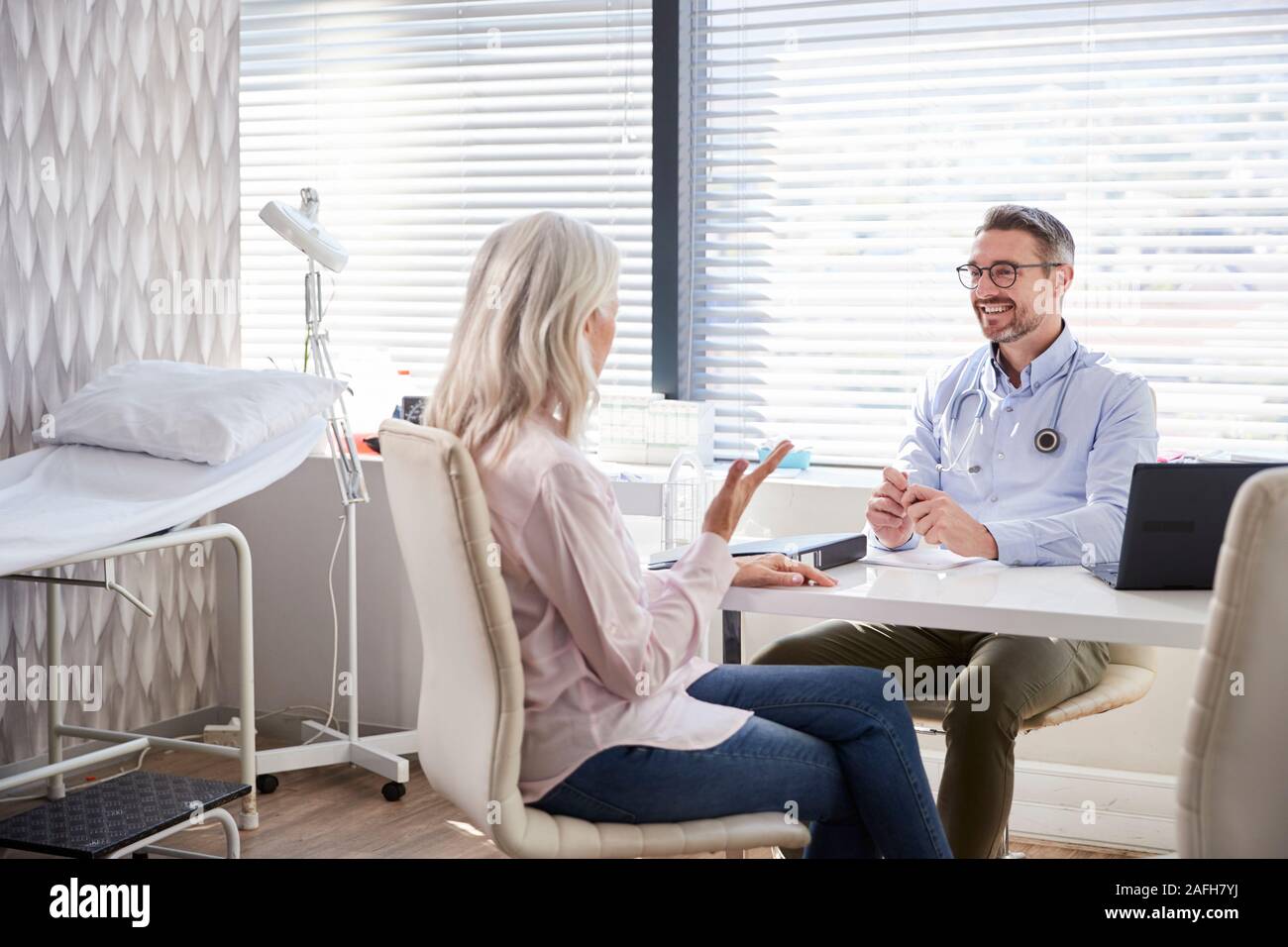 Femelle adulte Patient en consultation avec Doctor Sitting At Desk In Office Banque D'Images