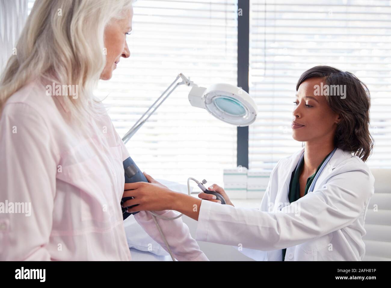 Patient femme ayant la pression artérielle prise par Female Doctor in Office Banque D'Images