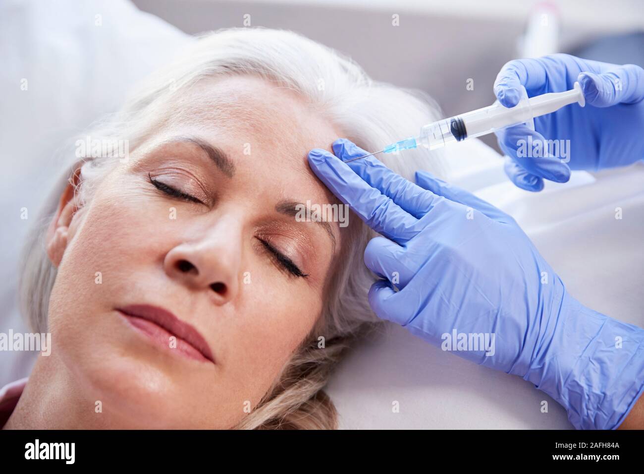 Femelle adulte donnant coiffeur injection de Botox dans le front du patient Banque D'Images
