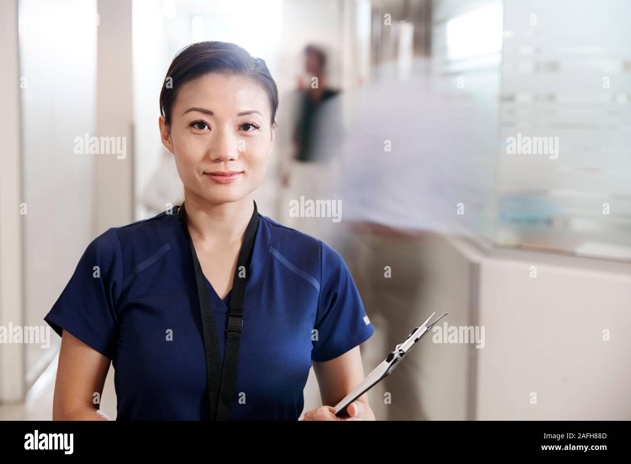 Portrait of Female Nurse Wearing Scrubs avec presse-papiers dans les couloir de l'hôpital Banque D'Images