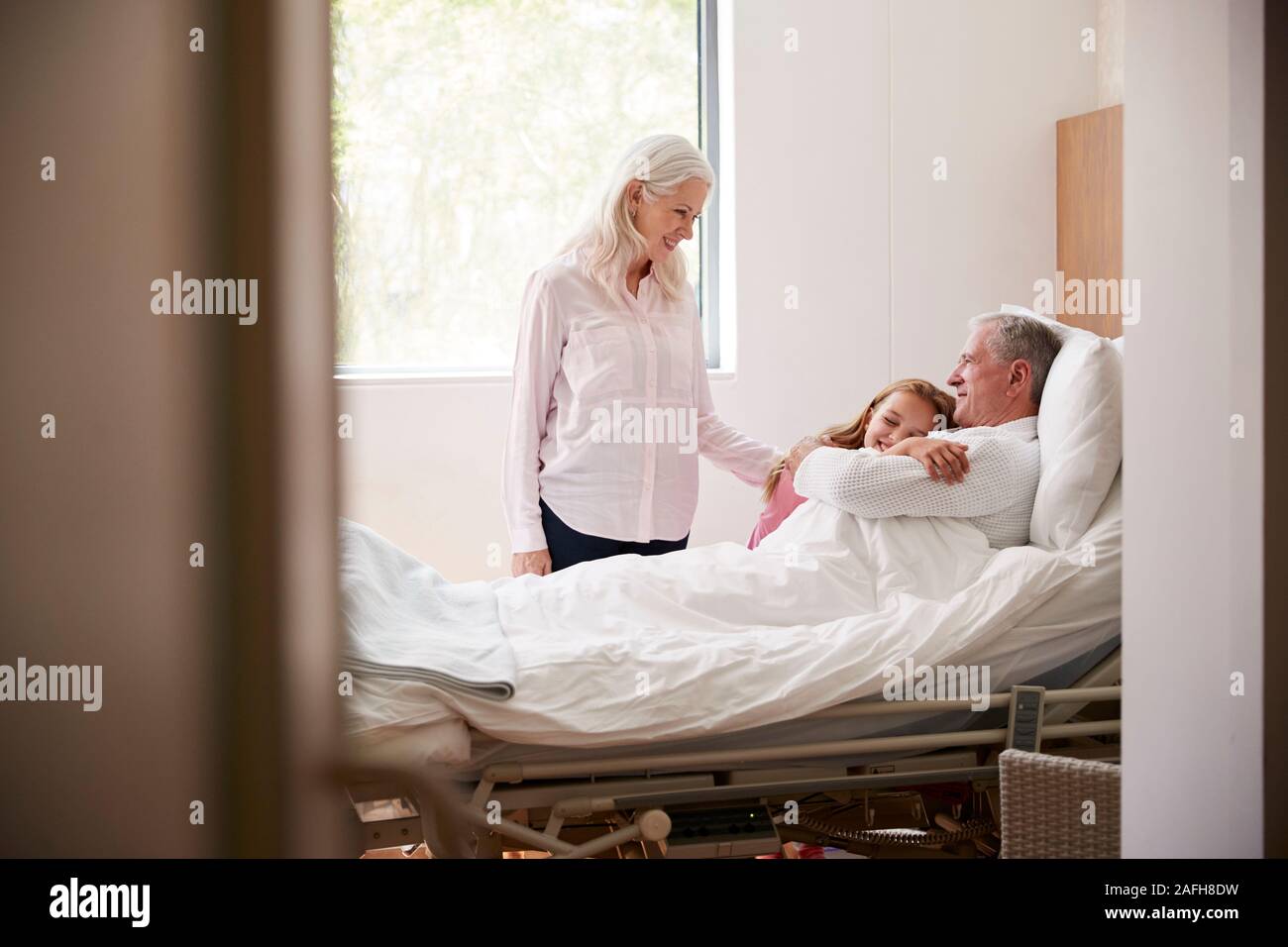 Granddaughter Hugging Grand-père sur la visite à l'hôpital. Banque D'Images