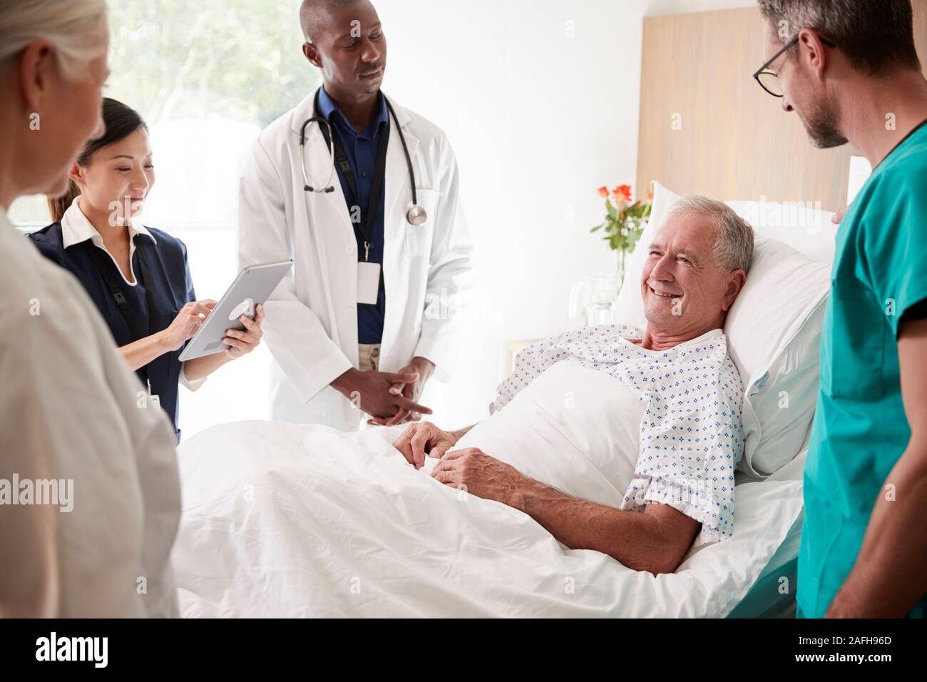 L'équipe médicale sur Tours rencontre autour du lit Senior Male Patient Banque D'Images