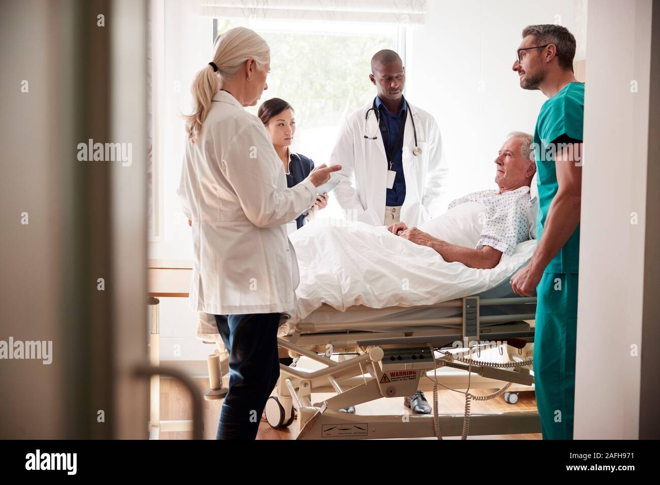 L'équipe médicale sur Tours rencontre autour du lit Senior Male Patient Banque D'Images