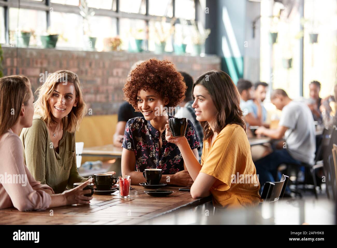Quatre jeunes femmes Réunion d'amis autour de la table à café et parler Banque D'Images
