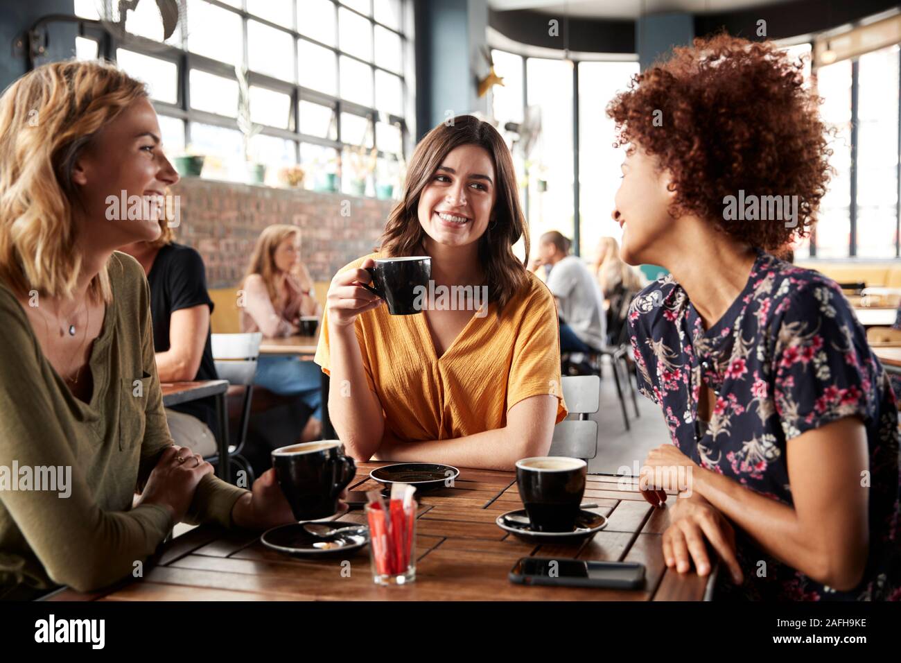 Trois jeunes femmes Réunion d'amis autour de la table à café et parler Banque D'Images