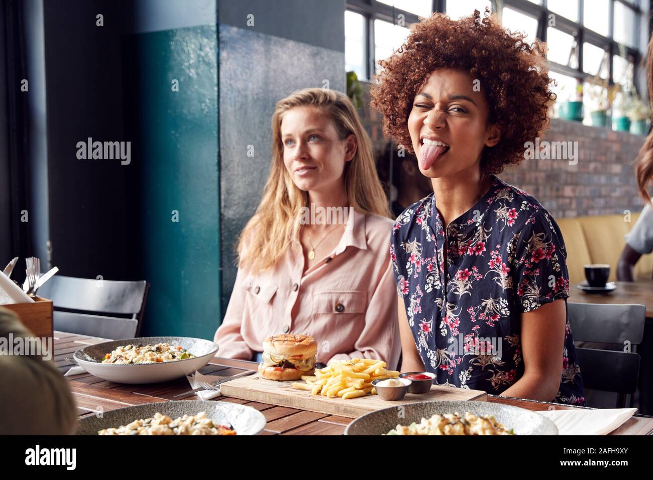 Woman Pulling Funny Face comme elle se réunit avec ses amis pour des boissons et de la nourriture dans le restaurant Banque D'Images