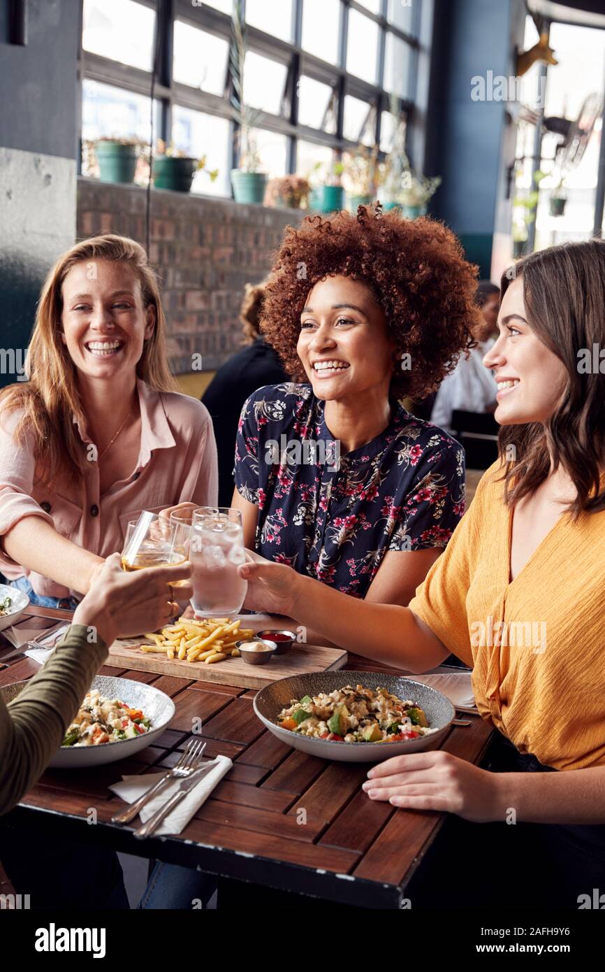 Quatre jeunes femmes Réunion d'amis pour les boissons et aliments de faire un toast en Restaurant Banque D'Images