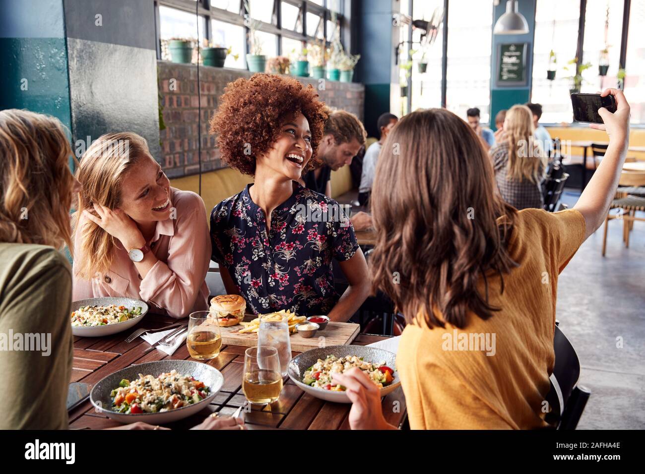 Quatre jeunes femmes Réunion d'amis pour des boissons et des aliments qui pose pour Restaurant En Selfies Banque D'Images