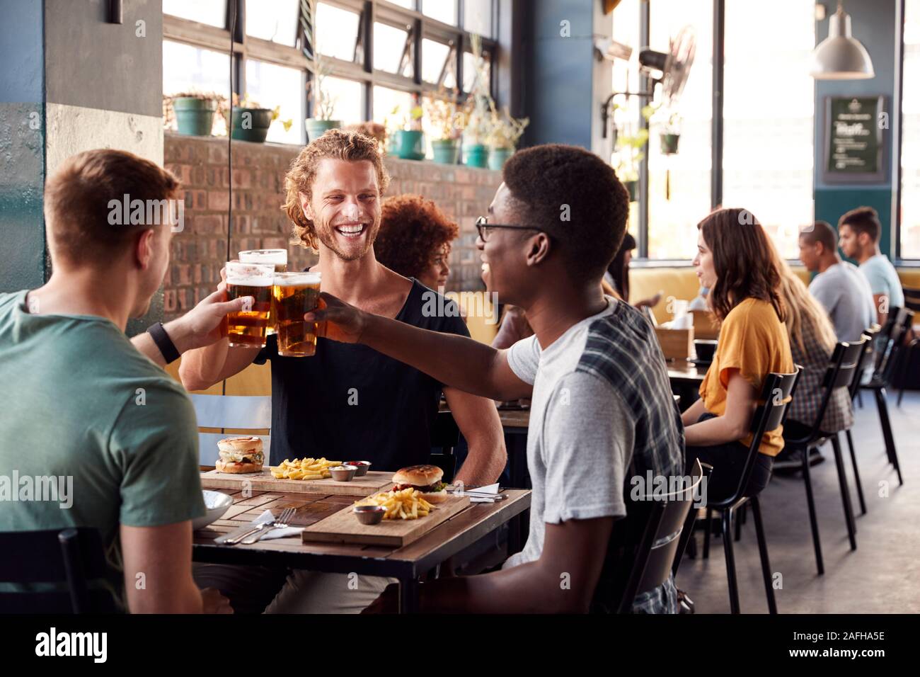 Trois jeunes amis réunion pour des boissons et de la nourriture faire un toast en Restaurant Banque D'Images
