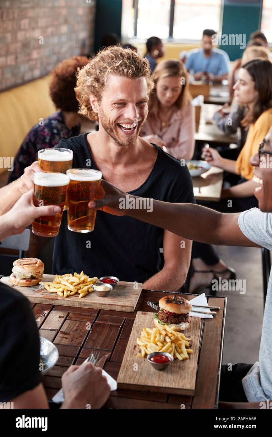 Trois jeunes amis réunion pour des boissons et de la nourriture faire un toast en Restaurant Banque D'Images