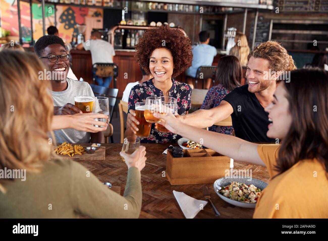 Groupe de jeunes amis réunion pour des boissons et de la nourriture faire un toast en Restaurant Banque D'Images