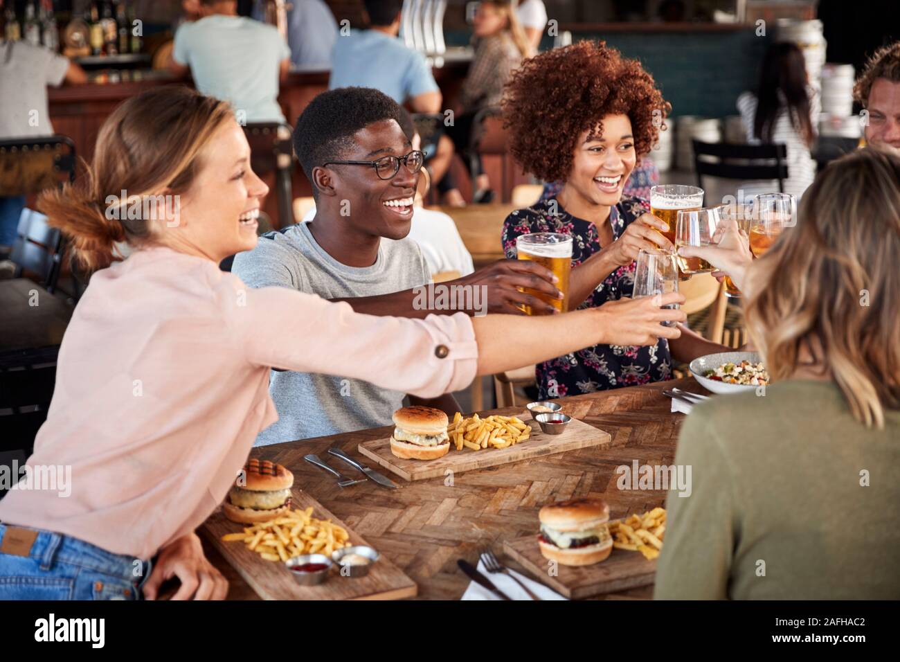 Groupe de jeunes amis réunion pour des boissons et de la nourriture faire un toast en Restaurant Banque D'Images