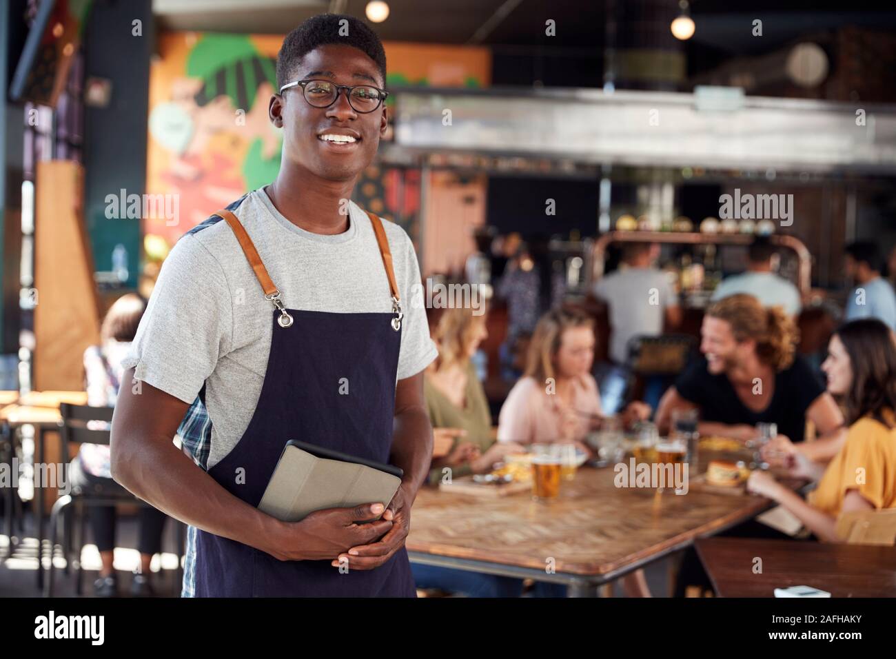 Portrait Of Waiter Serving in Busy Bar Restaurant Banque D'Images