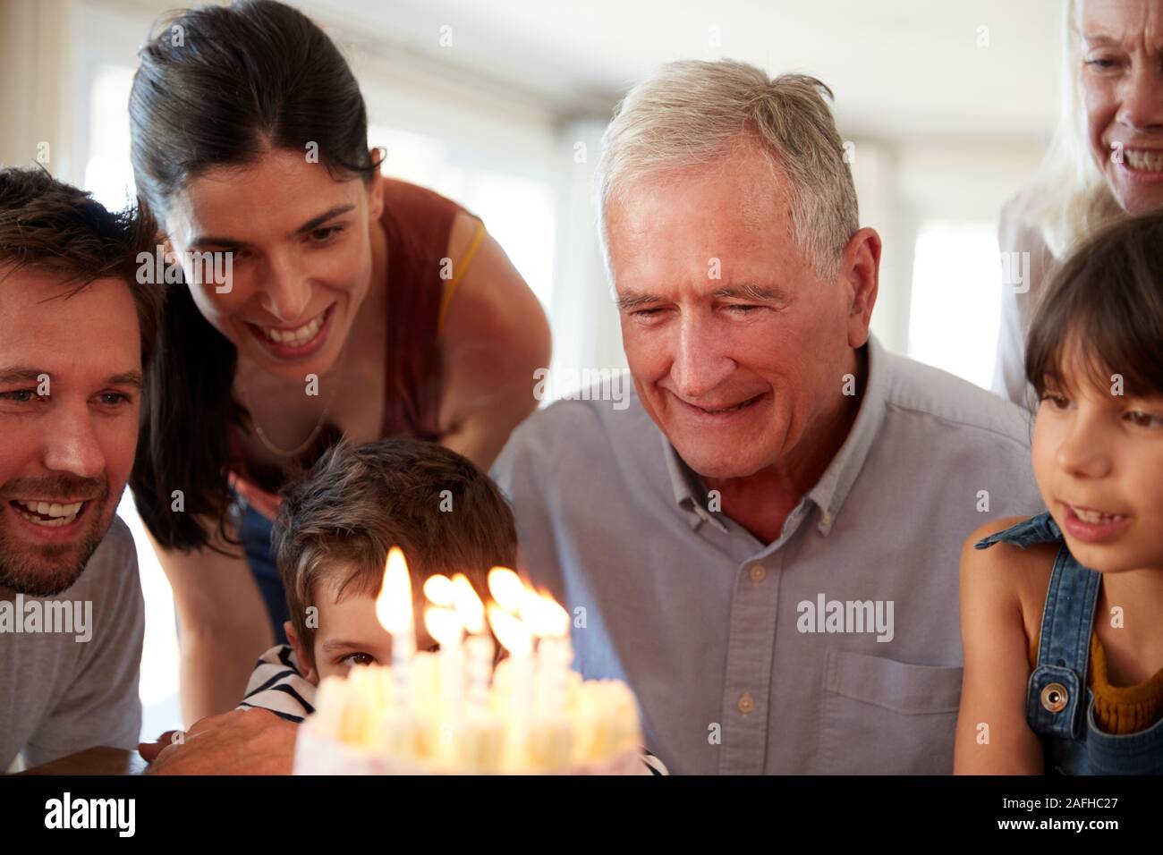 Hauts homme blanc et sa famille pour célébrer son anniversaire avec gâteau et bougies allumées, Close up Banque D'Images