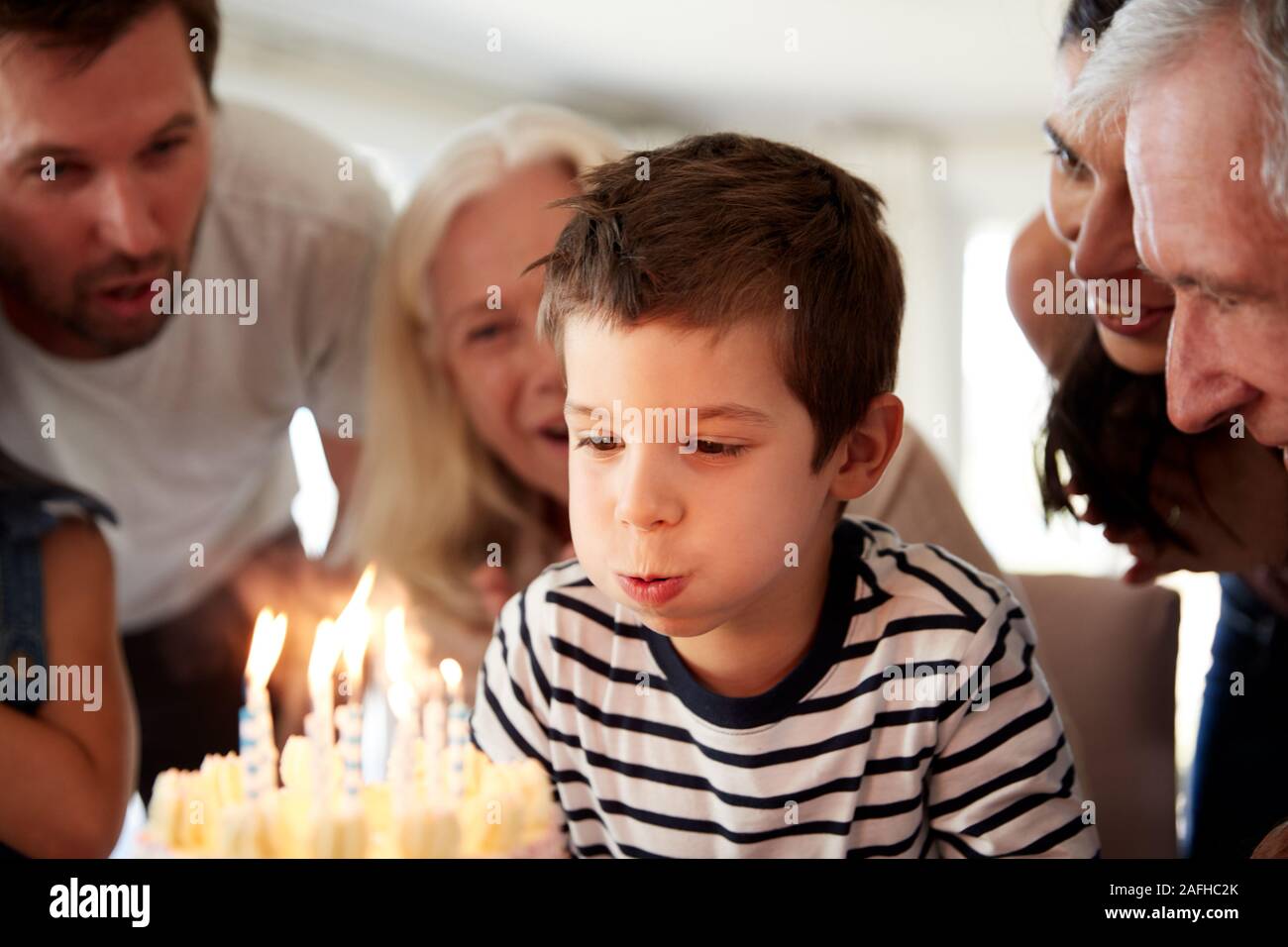 Quatre ans garçon blanc célébrer avec la famille blowing out candles sur son gâteau d'anniversaire, Close up Banque D'Images